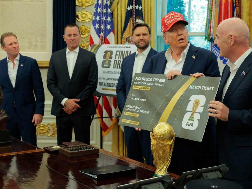 El presidente de la FIFA, Gianni Infantino, habla mientras él y el presidente de EE.UU., Donald Trump, sostienen una gran réplica de un boleto del Mundial en el Despacho Oval, mientras el vicepresidente JD Vance (tercero de izquierda) observa, el 22 de agosto de 2025 en Washington, DC. Trump anunció que el sorteo del Mundial 2026 de la FIFA se llevará a cabo en el Centro Kennedy.