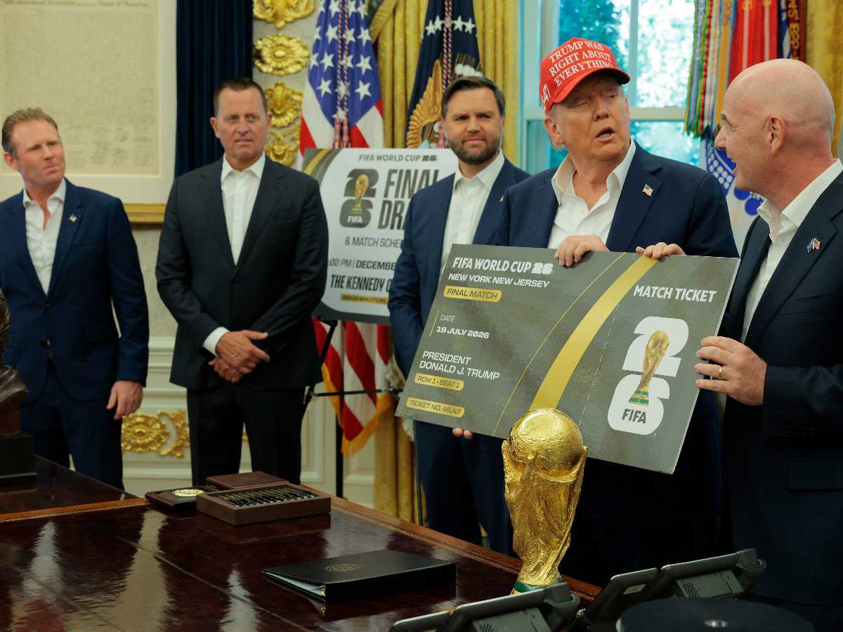 El presidente de la FIFA, Gianni Infantino, habla mientras él y el presidente de EE.UU., Donald Trump, sostienen una gran réplica de un boleto del Mundial en el Despacho Oval, mientras el vicepresidente JD Vance (tercero de izquierda) observa, el 22 de agosto de 2025 en Washington, DC. Trump anunció que el sorteo del Mundial 2026 de la FIFA se llevará a cabo en el Centro Kennedy.