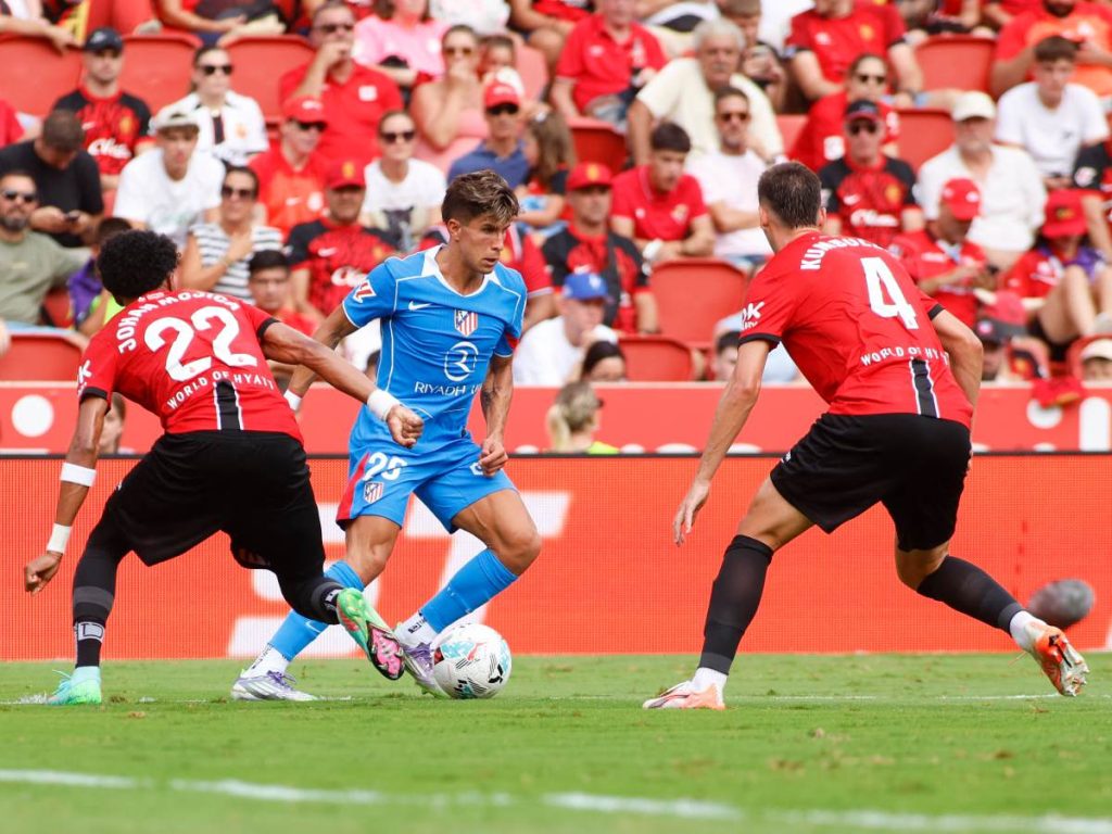 Guiliano Simeone (centro) controla el balón con marca de defensor Johan Mojica (izq.) Foto AFP