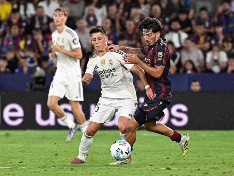 El turco Arda Güler, del Real Madrid, pelea por el balón contra el volante español Unai Vencedor, del Levante. / AFP