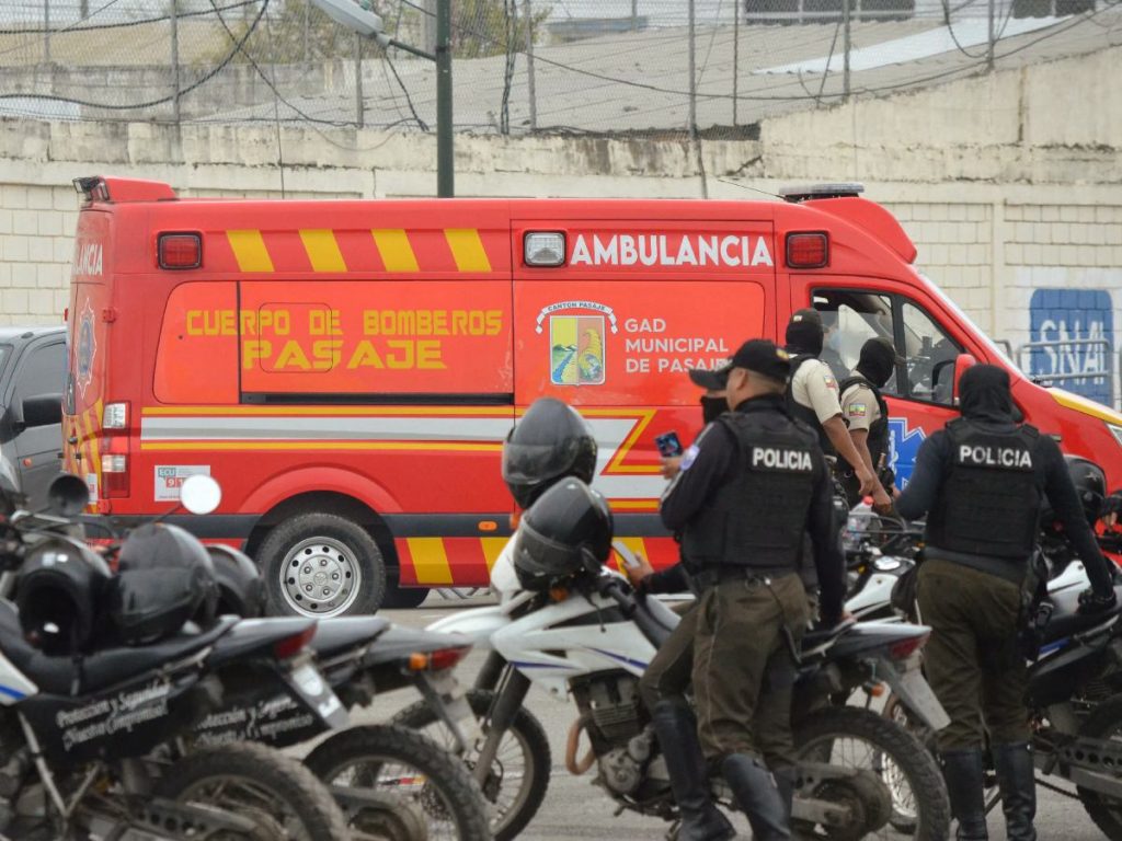 Policías resguardan una ambulancia frente a la cárcel de Machala tras los enfrentamientos que dejaron 14 muertos.