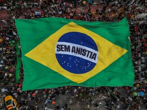 Esta vista aérea muestra a personas portando una enorme bandera brasileña con la leyenda 