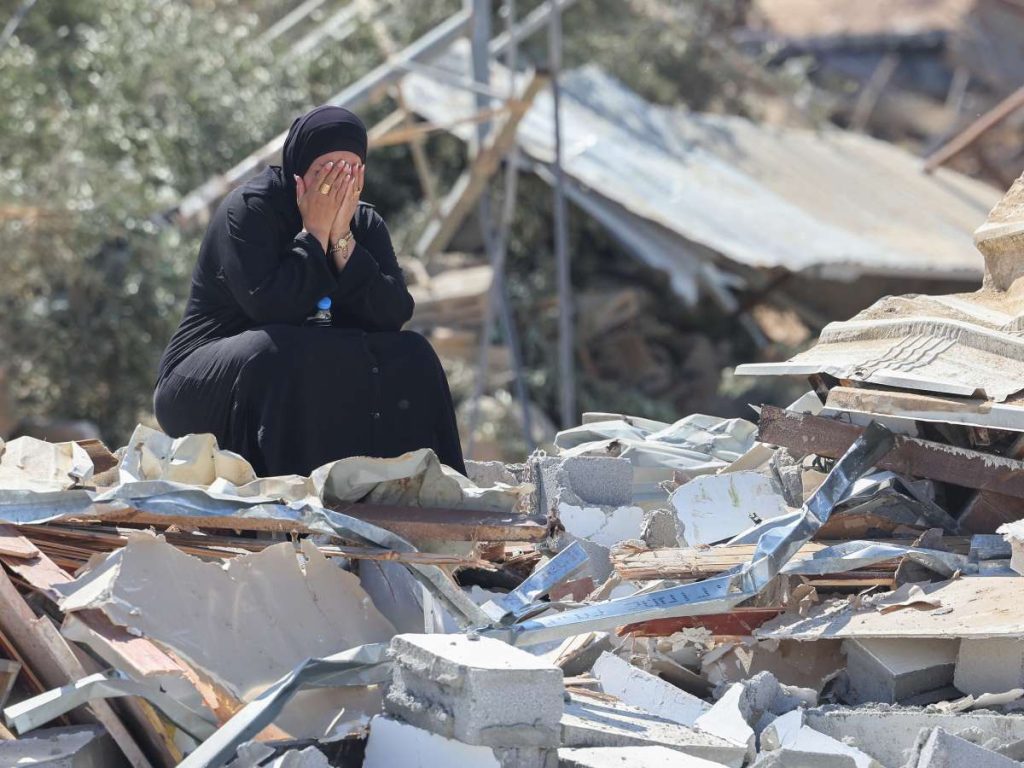 Una mujer beduina se cubre el rostro sentada entre los escombros de una vivienda construida sin permiso, demolida por las fuerzas israelíes en la aldea no reconocida de As-Sir, en el desierto del Néguev.