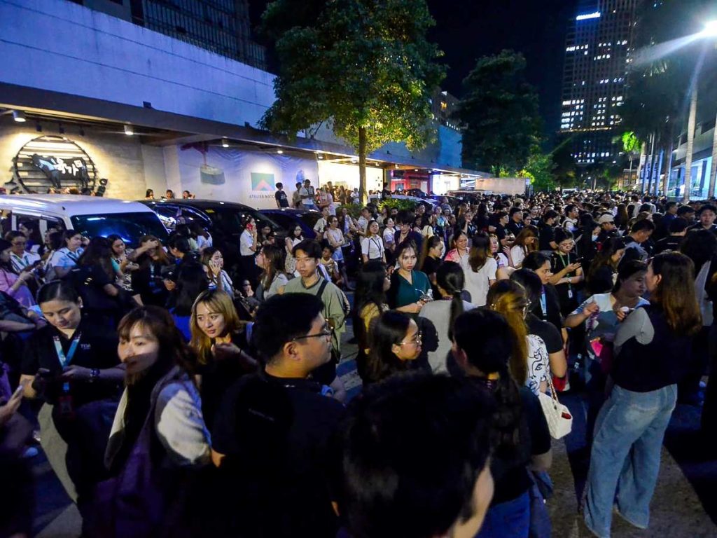 Los empleados de un centro de llamadas navegan por sus teléfonos móviles mientras se reúnen frente a su edificio de oficinas tras el terremoto en Cebú, en el centro de Filipinas.