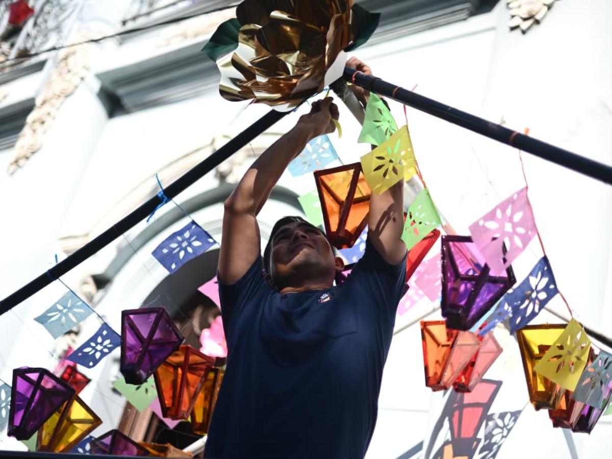 Un hombre colocando farolitos en el festival 2025