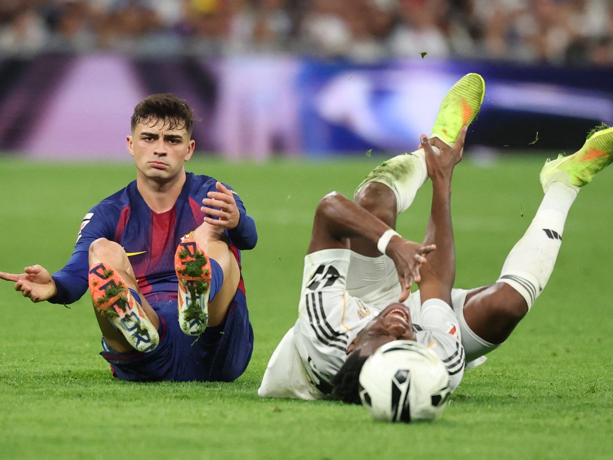 El centrocampista español #08 del Barcelona Pedri (izq.) comete falta sobre el centrocampista francés #14 del Real Madrid Aurelien Tchouameni durante el partido de fútbol de la liga española entre el Real Madrid CF y el FC Barcelona