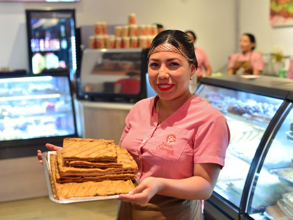 Una colaboradora de Panadería Santa Eduvigis muestra con orgullo las tradicionales semitas, elaboradas con recetas artesanales que han perdurado por 70 años.