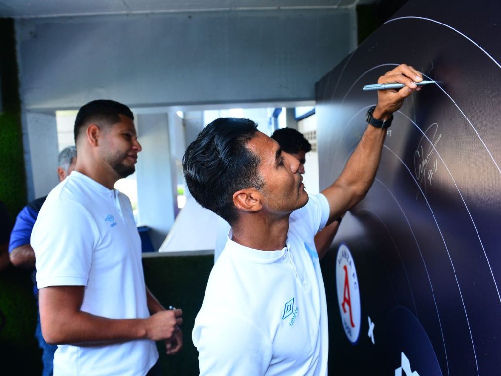 Jugadores de Alianza FC participan firmando el mural simbólico del nuevo convenio entre el club y la plataforma financiera Monetae.
