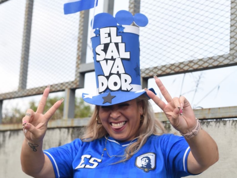 Con una gran sonrisa y un sombrero que grita “El Salvador”, la aficionada contagia alegría y optimismo antes del partido de la Selecta.