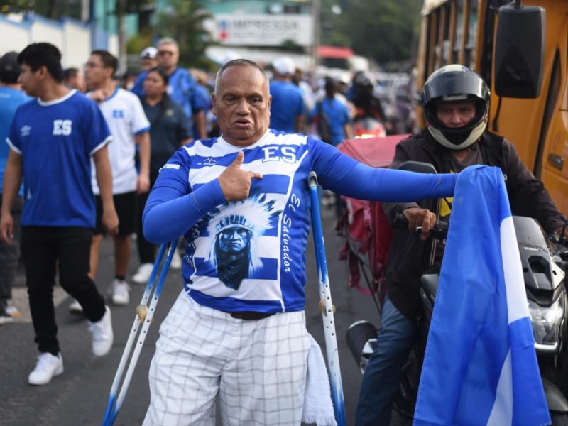 Un aficionado muestra con orgullo su camiseta y la bandera azul y blanco, reflejando la pasión inquebrantable por la Selecta, sin importar los desafíos.