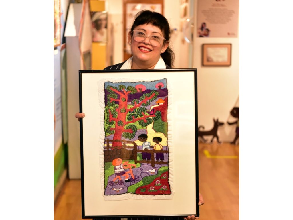 Karla Valle con uno de sus bordados inspirados en Cuentos de Cipotes. Fotografía/ elsalvador.com