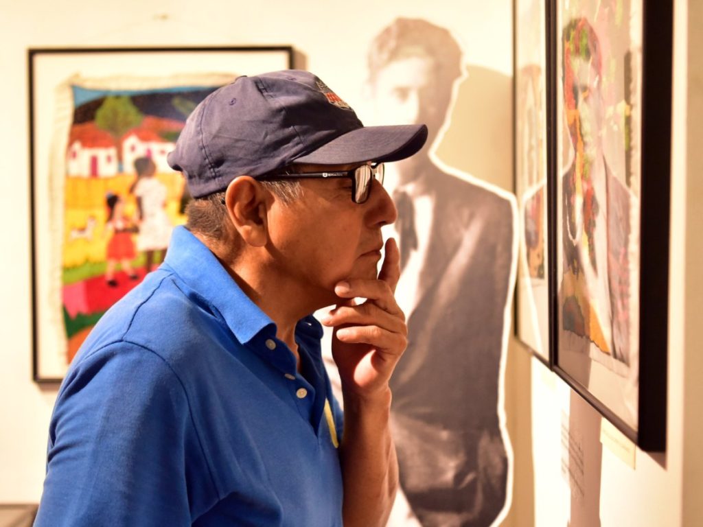 Un visitante observa de cerca los finos detalles del bordado inspirado en Cuentos de Cipotes, admirando la precisión y el color del trabajo artesanal. Fotografía/ elsalvador.com