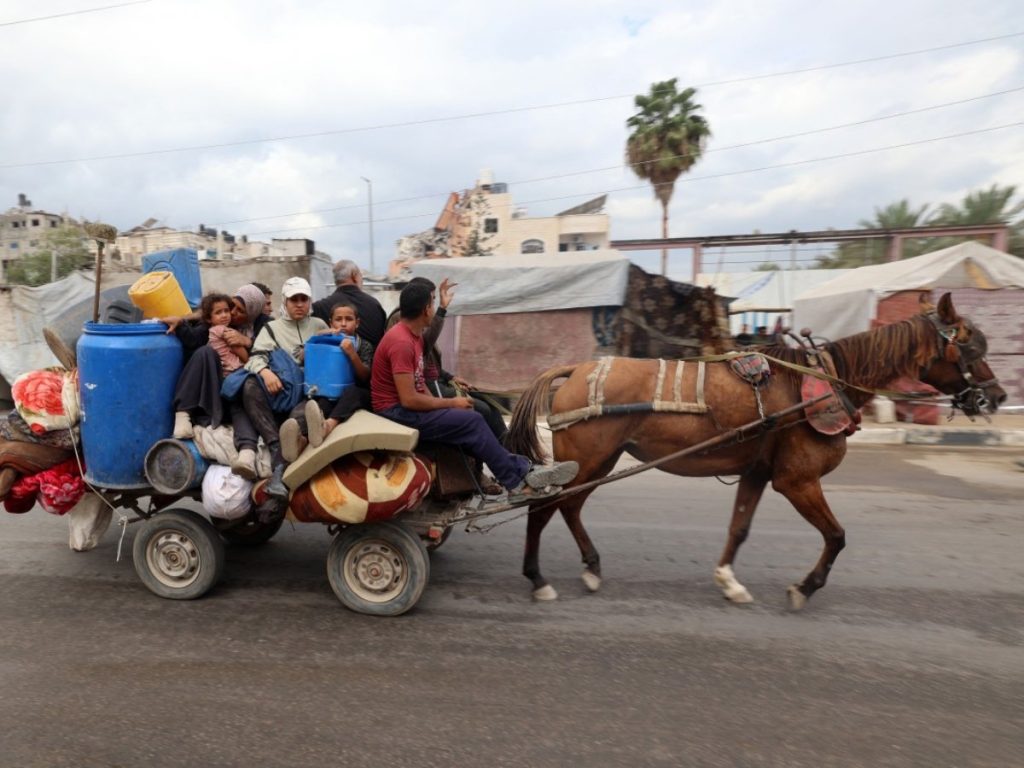 Palestinos desplazados viajan en una carreta tirada por caballos con sus pertenencias mientras atraviesan el campo de refugiados de Nuseirat, en el centro de la Franja de Gaza, rumbo a la Ciudad de Gaza, el 12 de octubre de 2025. Foto/ AFP