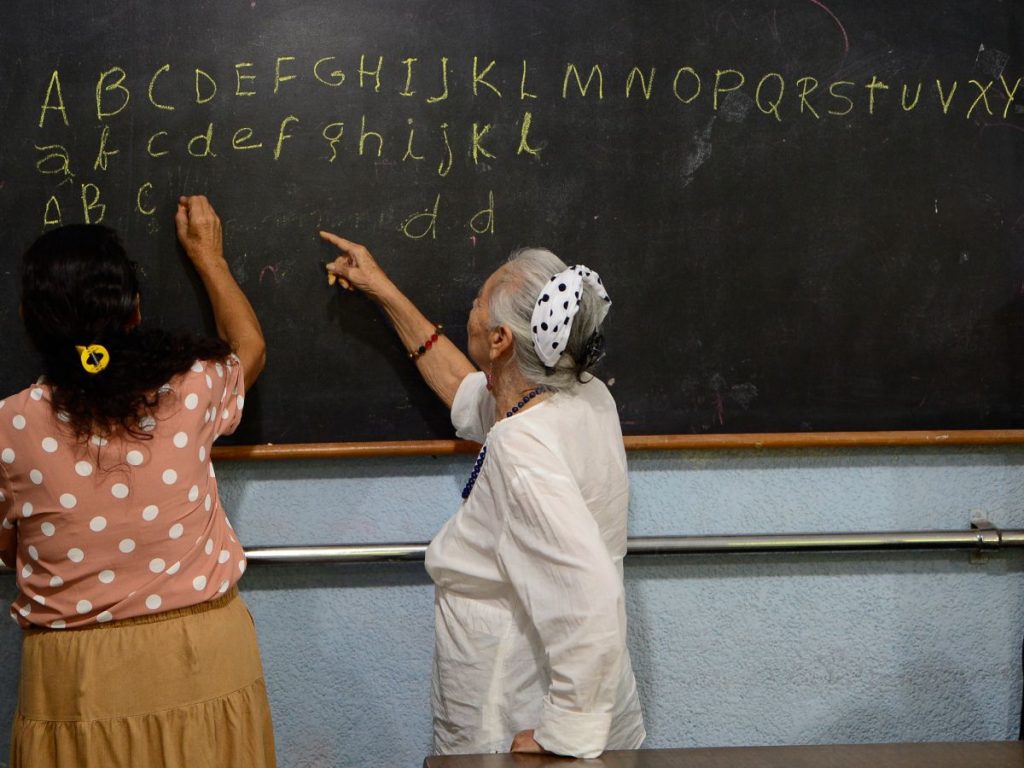 Natividad, junto a Maribel, repasan las letras minúsculas y mayúsculas del abecedario como parte de la clase. Foto/ elsalvador.com