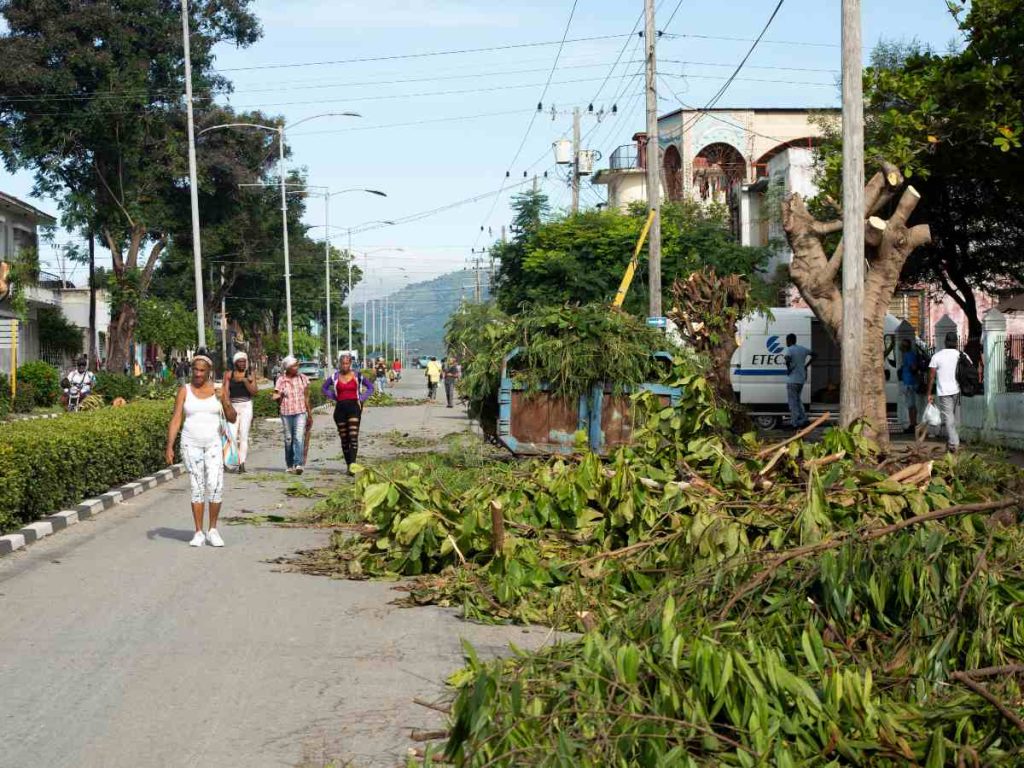 La gente camina entre ramas de árboles podados antes de la llegada de la tormenta tropical Melissa a Santiago de Cuba el 25 de octubre de 2025.