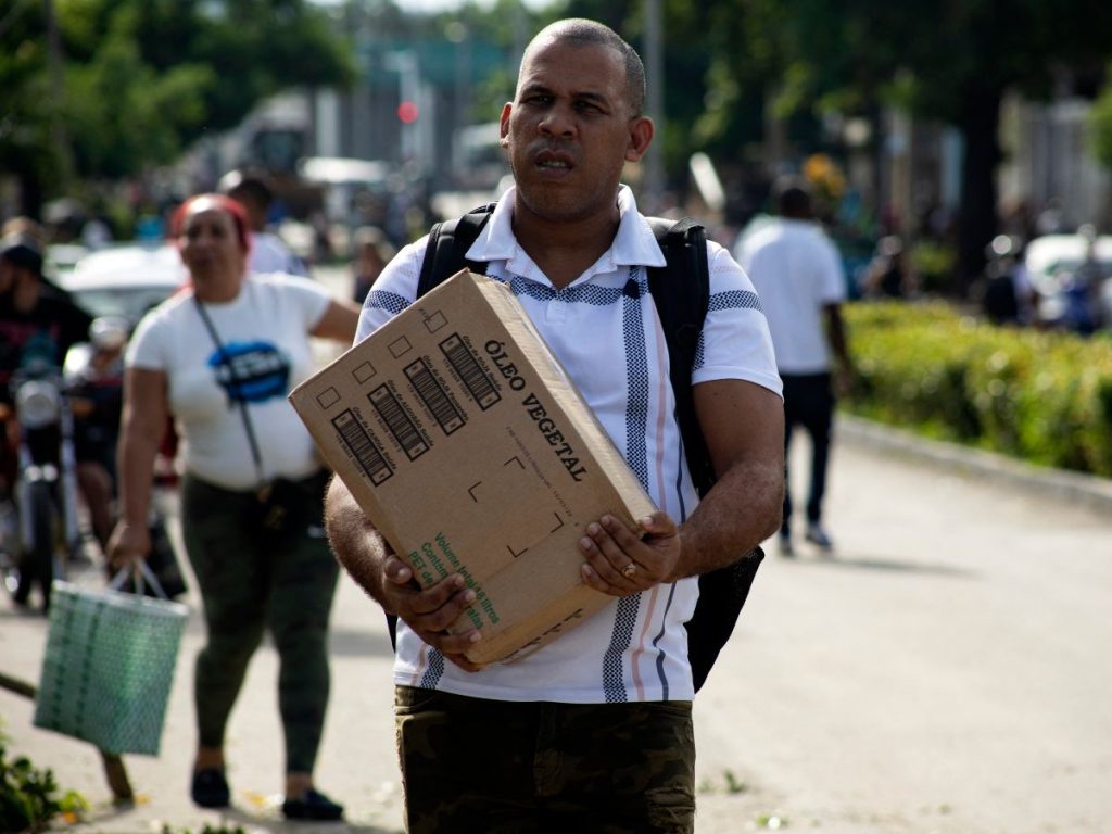 Un hombre carga una caja de aceite de cocina antes de la llegada de la tormenta tropical Melissa a Santiago de Cuba el 25 de octubre de 2025.