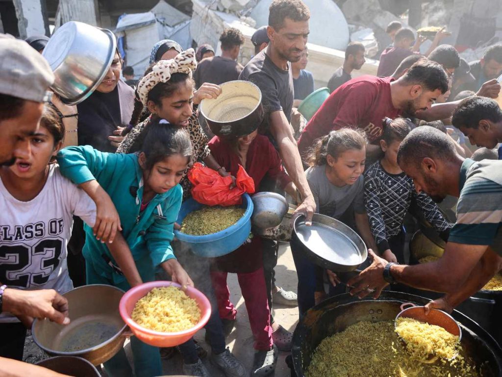 Familias gazatíes recibiendo alimentos en un centro de distribución, en medio de la persistente escasez tras la tregua entre Israel y Hamás.