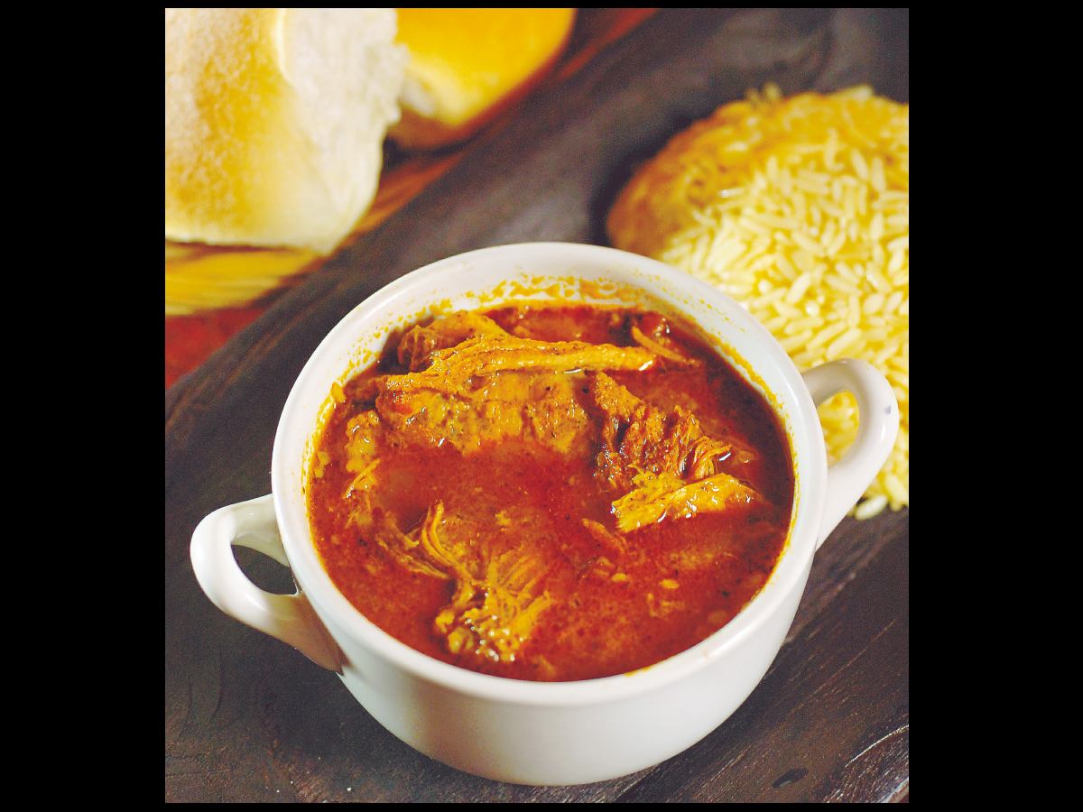 Cochinita salvadoreña: carne de cerdo en salsa espesa de especias, servida con arroz y pan. Un platillo típico de Atiquizaya que honra la tradición y el sabor.