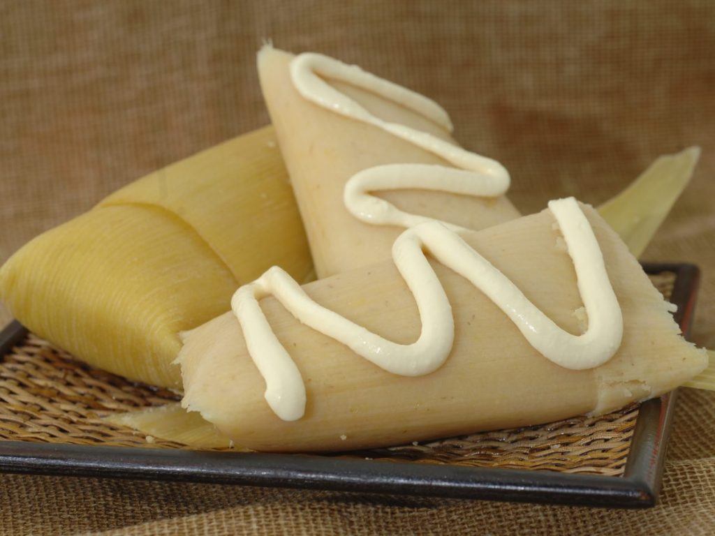 Los tamales de elote, suaves y dulces, envueltos en hojas y cocidos al vapor, son un clásico salvadoreño que evoca tradición y sabor de hogar.