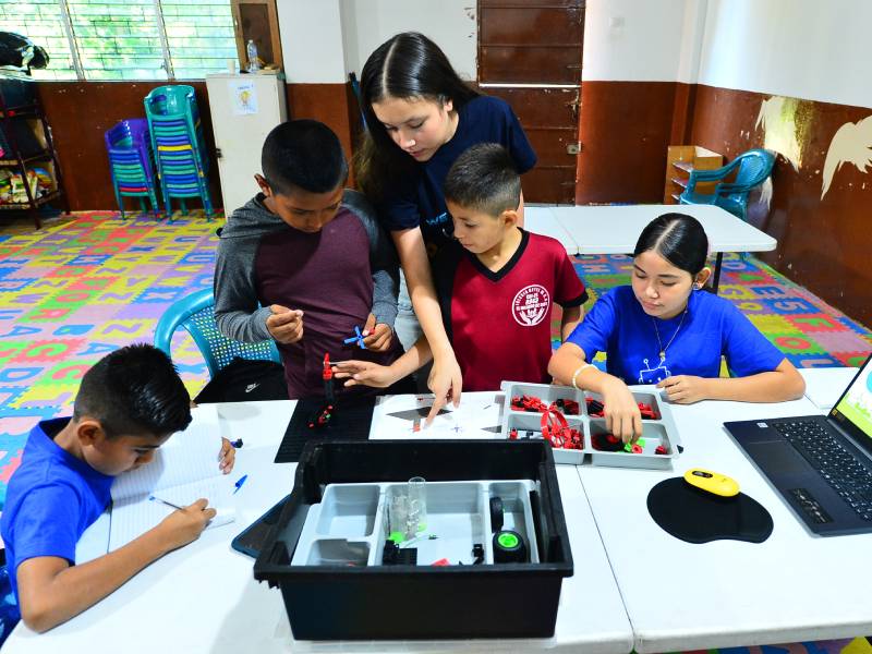 Instructores guían a los niños participantes en prácticas de programación y diseño tecnológico.