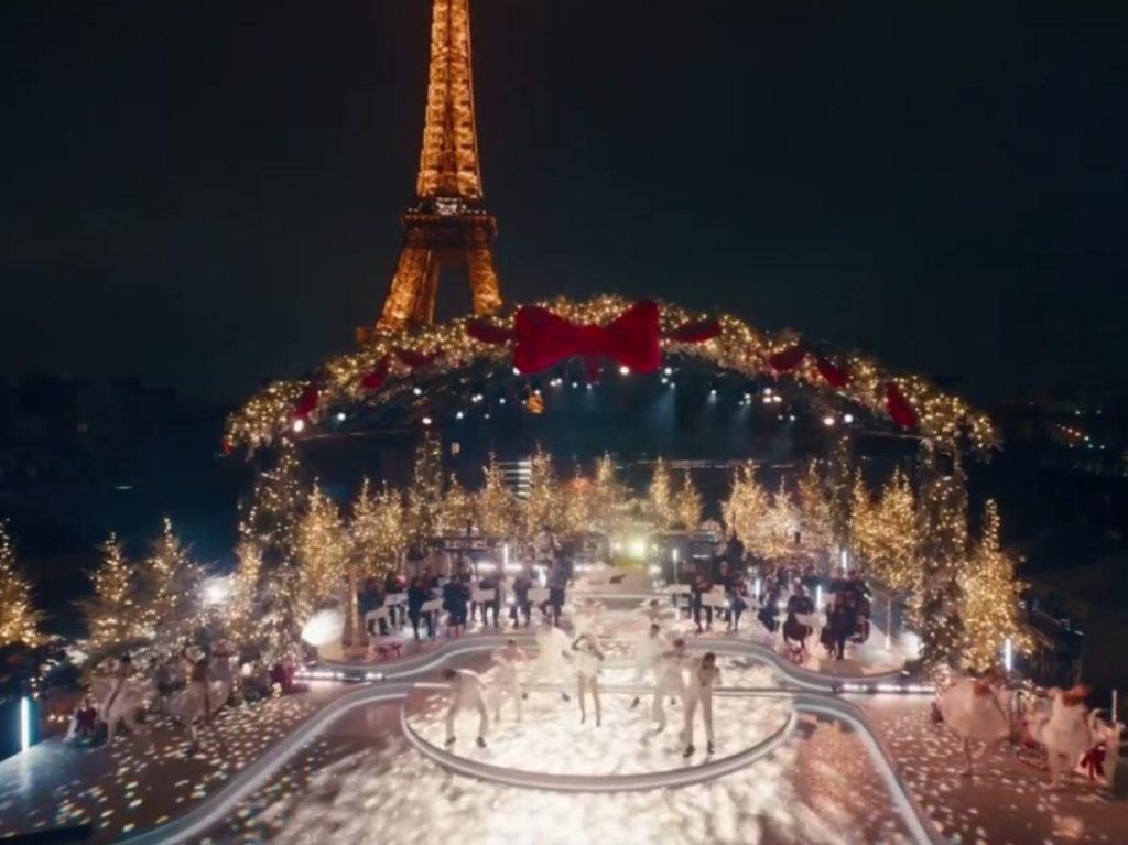 Escenario iluminado frente a la Torre Eiffel durante la grabación de Christmas in Paris, donde música, coreografía y decoración crean una postal festiva.