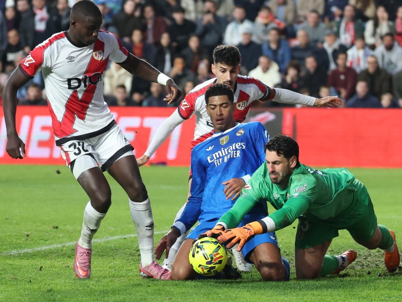 Augusto Batalla, arquero del Rayo Vallecano, logra frenar un ataque del inglés Jude Bellingham, del Real Madrid (azul). / Foto AFP