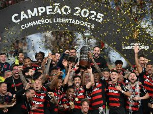 El delantero del Flamengo #27 Bruno Henrique (D) y el mediocampista uruguayo #10 Giorgian de Arrascaeta (I) levantan el trofeo con sus compañeros de equipo después de ganar la final de la Copa Libertadores de Brasil entre Palmeiras y Flamengo en el estadio Monumental 'U' Marathon de Lima el 29 de noviembre de 2025. (Foto AFP)