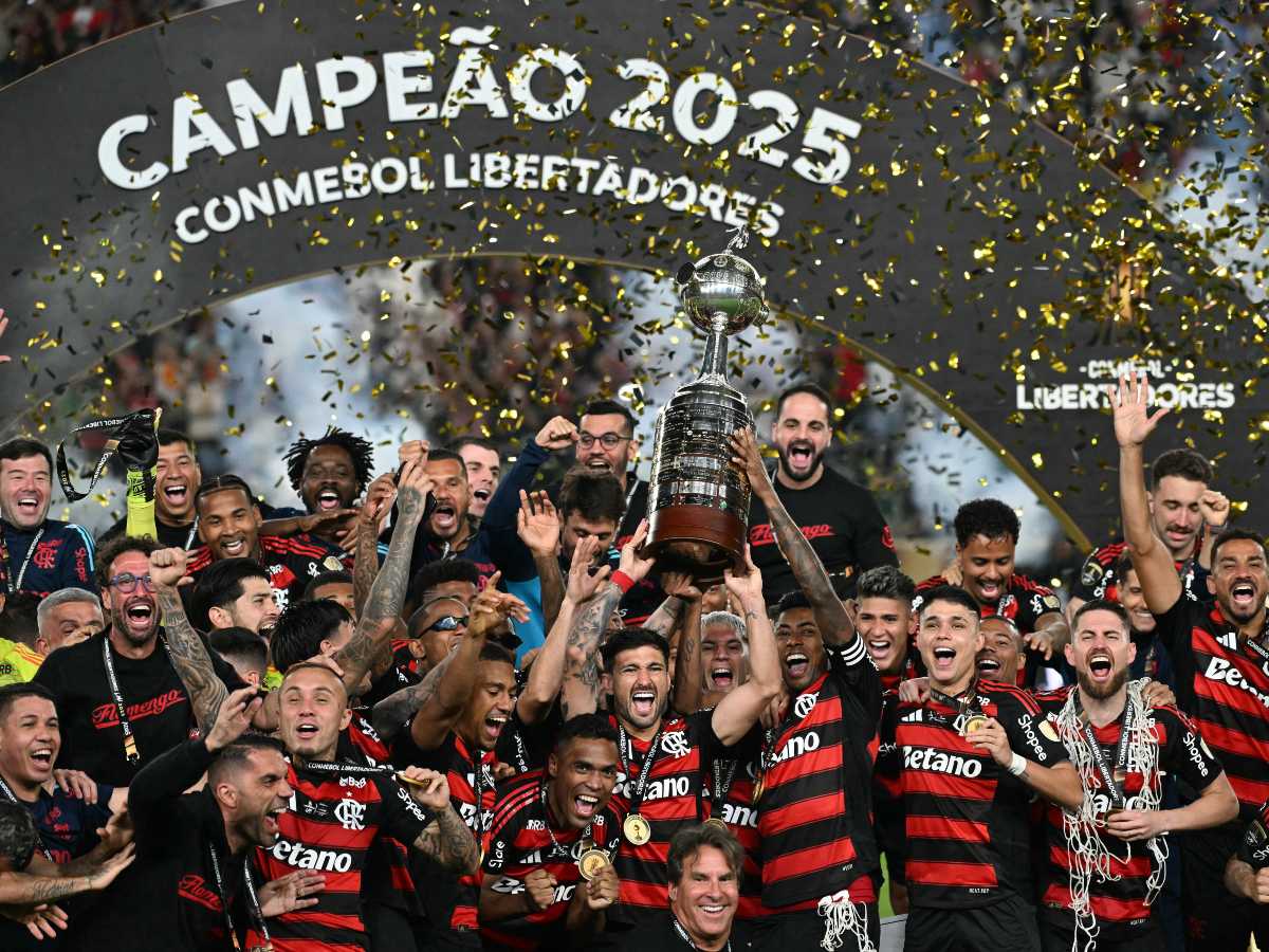 El delantero del Flamengo #27 Bruno Henrique (D) y el mediocampista uruguayo #10 Giorgian de Arrascaeta (I) levantan el trofeo con sus compañeros de equipo después de ganar la final de la Copa Libertadores de Brasil entre Palmeiras y Flamengo en el estadio Monumental 'U' Marathon de Lima el 29 de noviembre de 2025. (Foto AFP)