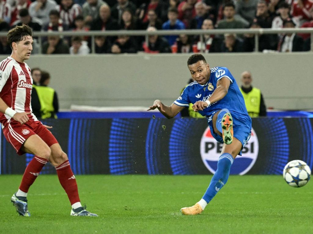 El delantero francés #10 del Real Madrid, Kylian Mbappé (R), dispara para marcar el tercer gol de su equipo durante la quinta jornada de la fase de liga de la UEFA Champions League, partido de fútbol entre Olympiakos (GRE) y Real Madrid (ESP) en el estadio Georgios Karaiskakis de El Pireo el 26 de noviembre de 2025. AFP 