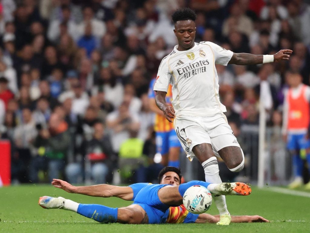 Vinicius Junior, del Real Madrid, con marca de defensa del Valencia. Foto AFP
