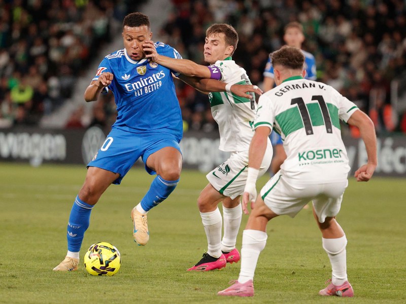 El delantero francés Kilyan Mbappé, del Real Madrid, intenta escapar de dos rivales del Elche. / Foto EFE