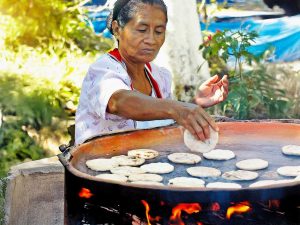 Salvadoreña prepara pupusas en comal de barro, una tradición que enciende el alma y el sabor del país, celebrada cada segundo domingo de noviembre.