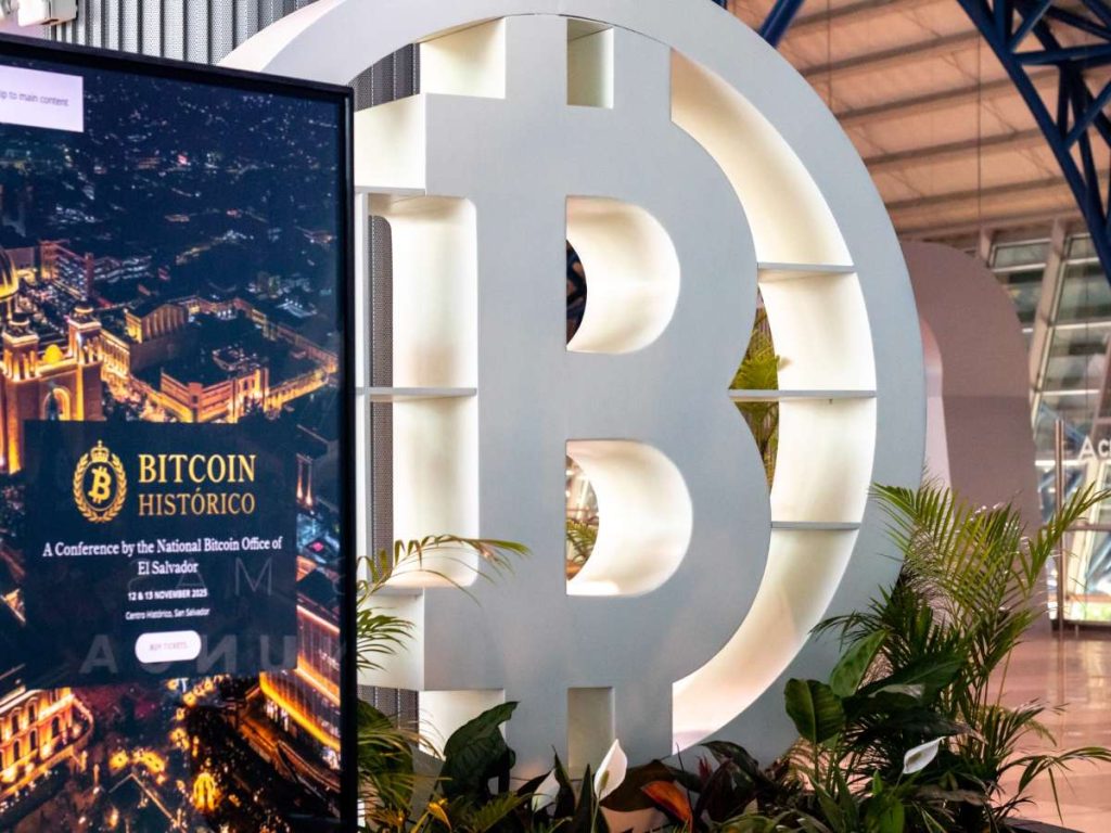 Detalle del punto de información “Bitcoin Country Booth” en el aeropuerto, que promociona el evento “Bitcoin Histórico”, programado del 12 al 15 de noviembre en San Salvador.