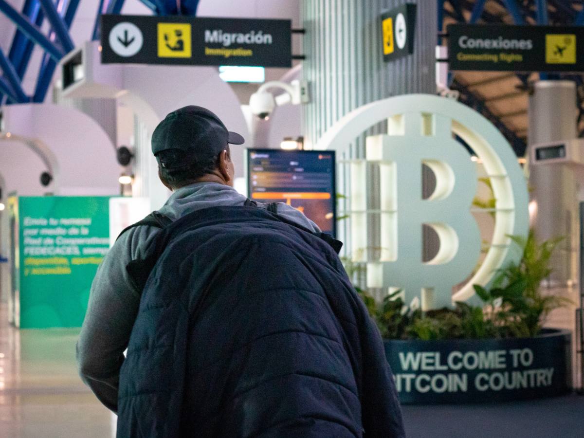 Un viajero llega al Aeropuerto Internacional de San Salvador, donde un letrero da la bienvenida a los visitantes con la frase “Welcome to Bitcoin Country”.