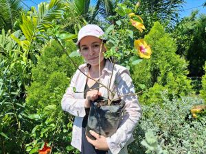 Jasmín riega parte de las plantas que reproduce en su vivero, donde combina frutales y especies ornamentales.
