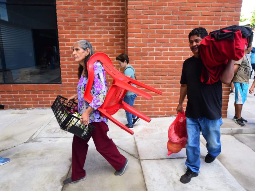 Comerciantes y sus familias ingresan al renovado edificio del Mercado San Miguelito cargando sus productos y mobiliario para acondicionar sus puestos.