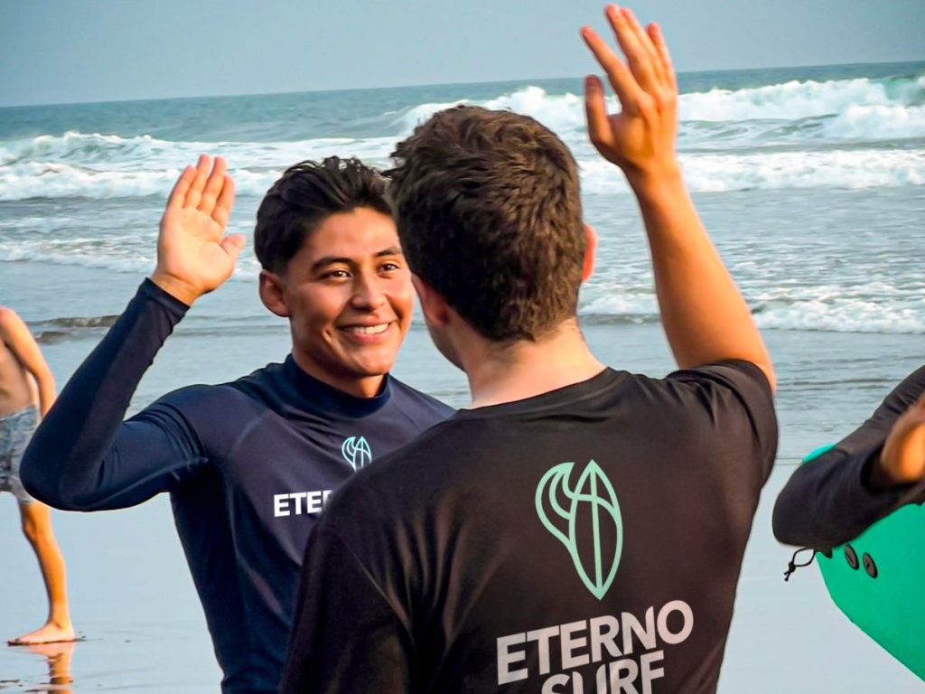 Instructores y alumnos celebran una sesión exitosa en Eterno Surf, una escuela con enfoque local y profesional.