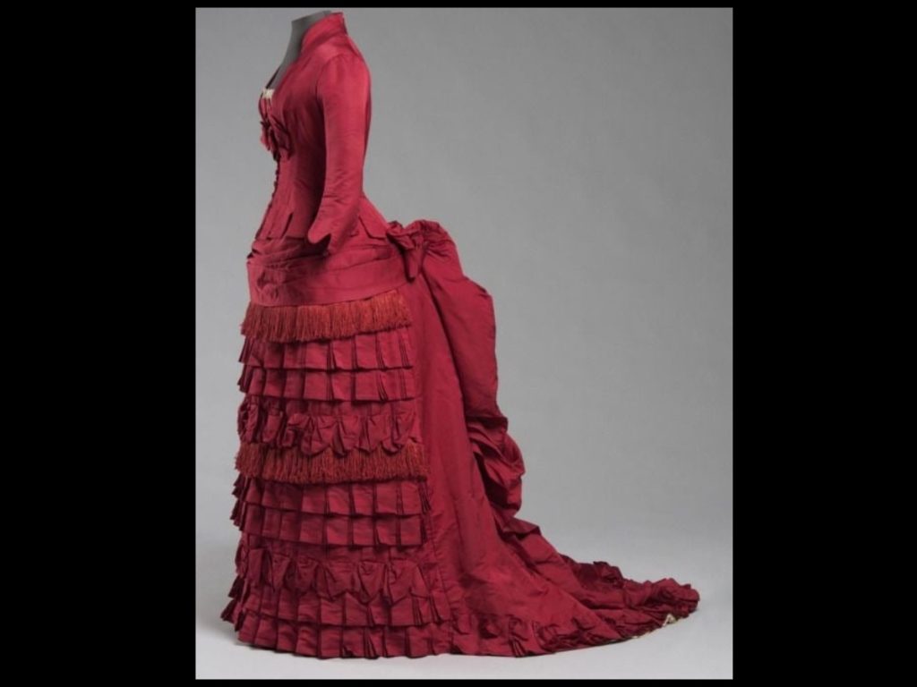 Vestido de Mme. Grapanche (1884–86), un ejemplo exquisito del esplendor del polisón tardío, donde el volumen posterior y los detalles artesanales definen la silueta victoriana.