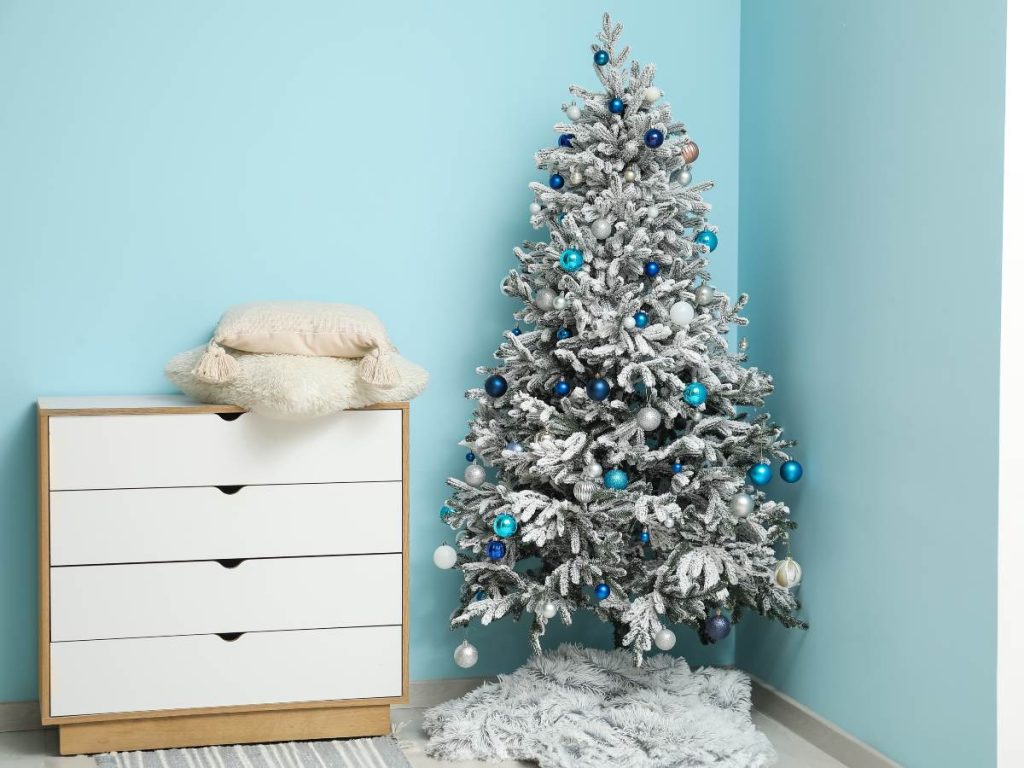Un árbol nevado con esferas en azul y blanco aporta un look moderno, ideal para espacios minimalistas o con paletas frías. Simple, limpio y festivo.