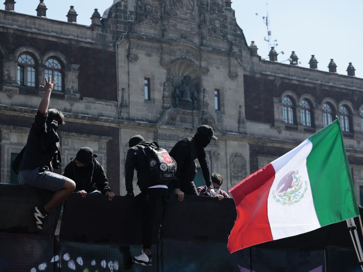 Manifestantes trepan por una valla durante una protesta este sábado, en inmediaciones del Palacio Nacional en Ciudad de México (México). Cientos de personas, muchos de ellos jóvenes de la llamada Generación Z, marcharon portando banderas de One Piece y coreando “¡Fuera Claudia!” en descontento hacia el gobierno de Sheinbaum y para denunciar la impunidad ante la creciente violencia en el país. EFE
