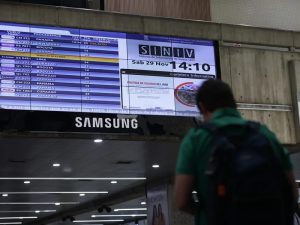 Fotografía de una persona caminando junto a una pantalla con la programación de vuelos, en el Aeropuerto Internacional Simón Bolívar, en Maiquetía (Venezuela).