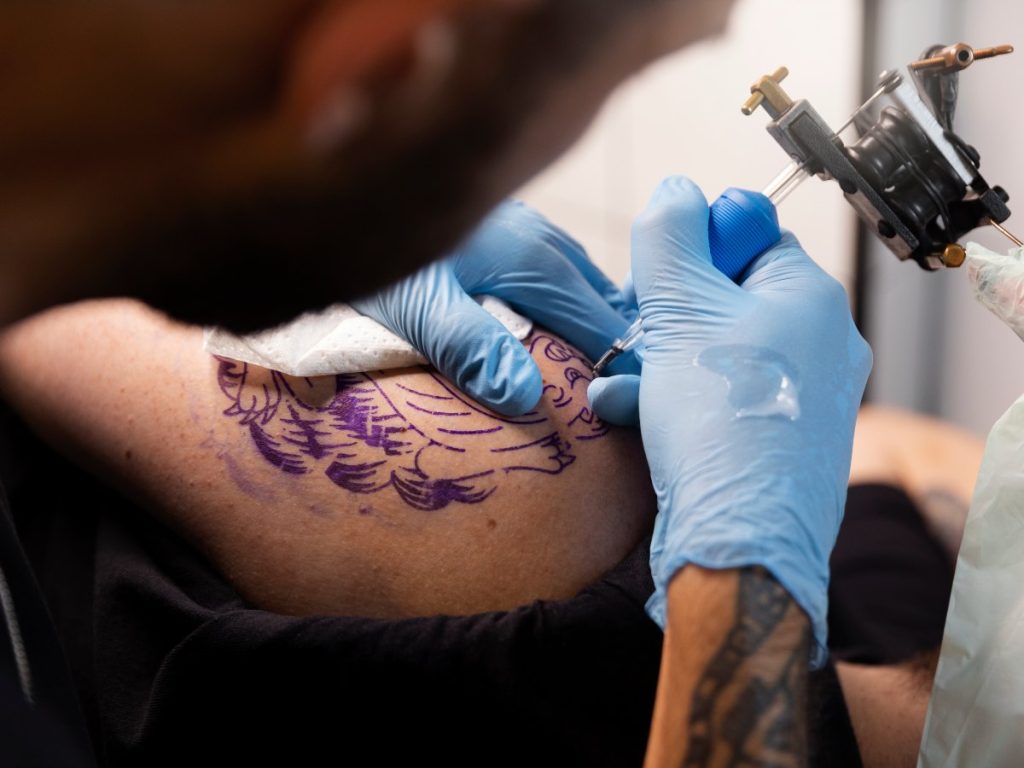 Un tatuador aplica tinta en la piel durante una sesión; el nuevo estudio analiza cómo estos pigmentos viajan dentro del cuerpo.