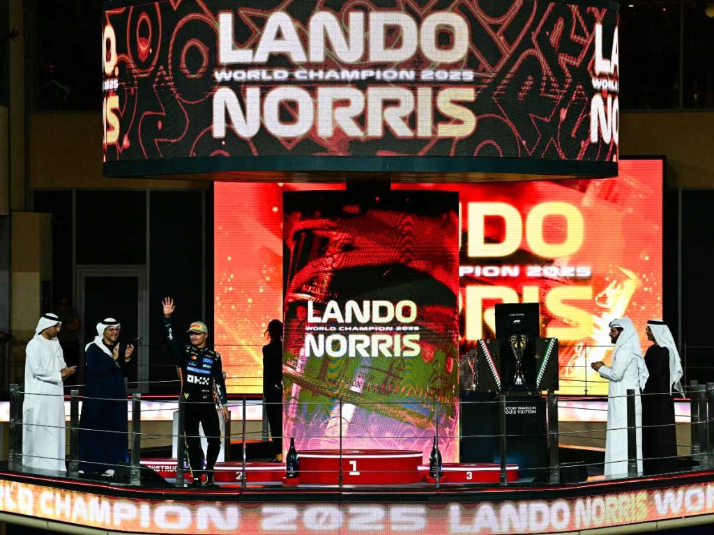 El piloto británico de McLaren, Lando Norris, saluda desde el podio tras terminar tercero en la carrera y ganar el título mundial al final del Gran Premio de Fórmula Uno de Abu Dabi, en el Circuito Yas Marina de Abu Dabi, el 7 de diciembre de 2025. (Foto AFP)