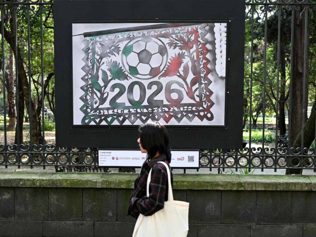 Una mujer camina junto a las acuarelas de Cynthia Saide con temática de la Copa Mundial de la FIFA 2026 en el Parque Chapultepec en la Ciudad de México el 5 de diciembre de 2025.