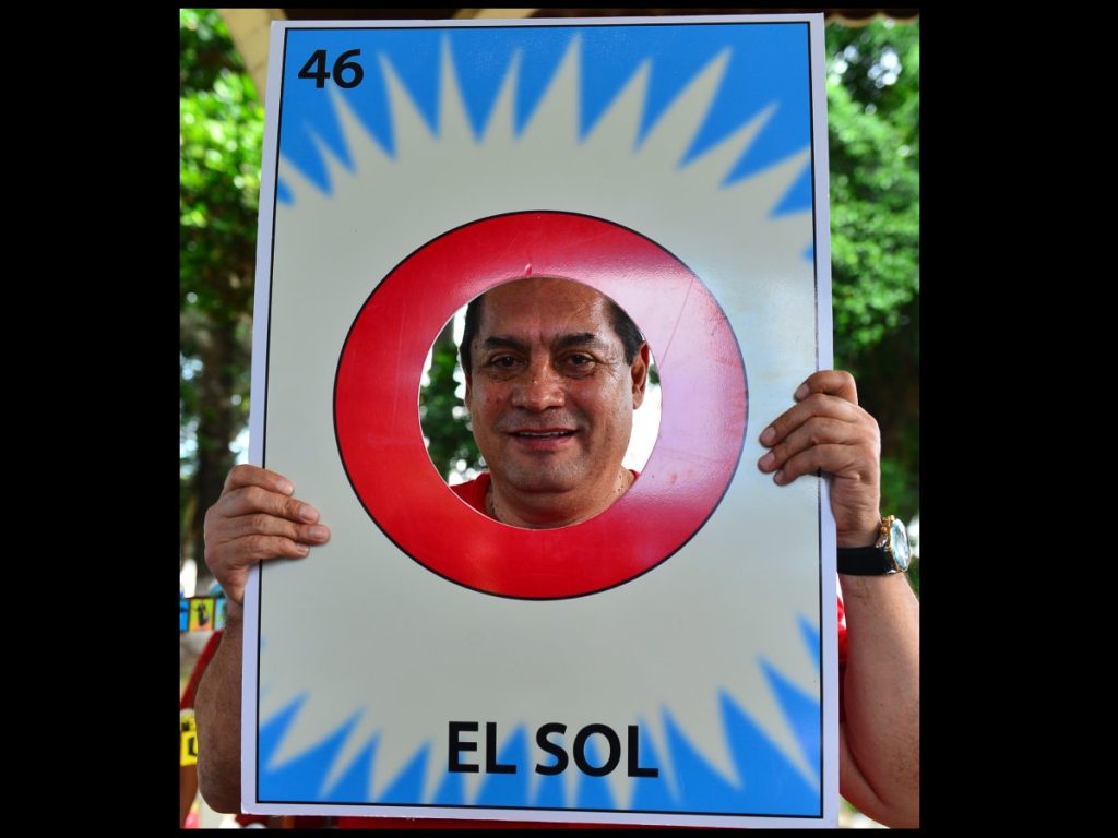 Con humor y creatividad, un participante posa tras la carta “El Sol”, símbolo del ingenio y la alegría que caracterizan la Lotería de Atiquizaya.