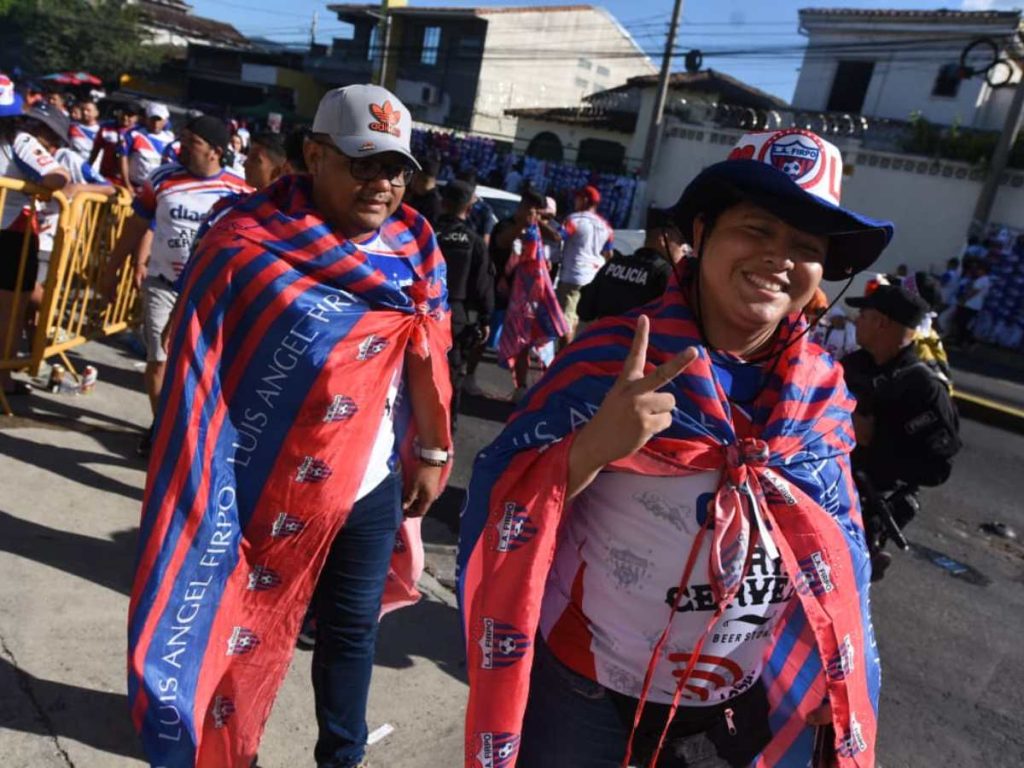 Aficionados de L.A. Firpo llegan envueltos en los colores azul y rojo a las inmediaciones del estadio Mágico González, mostrando el entusiasmo pampero en la previa de la final.