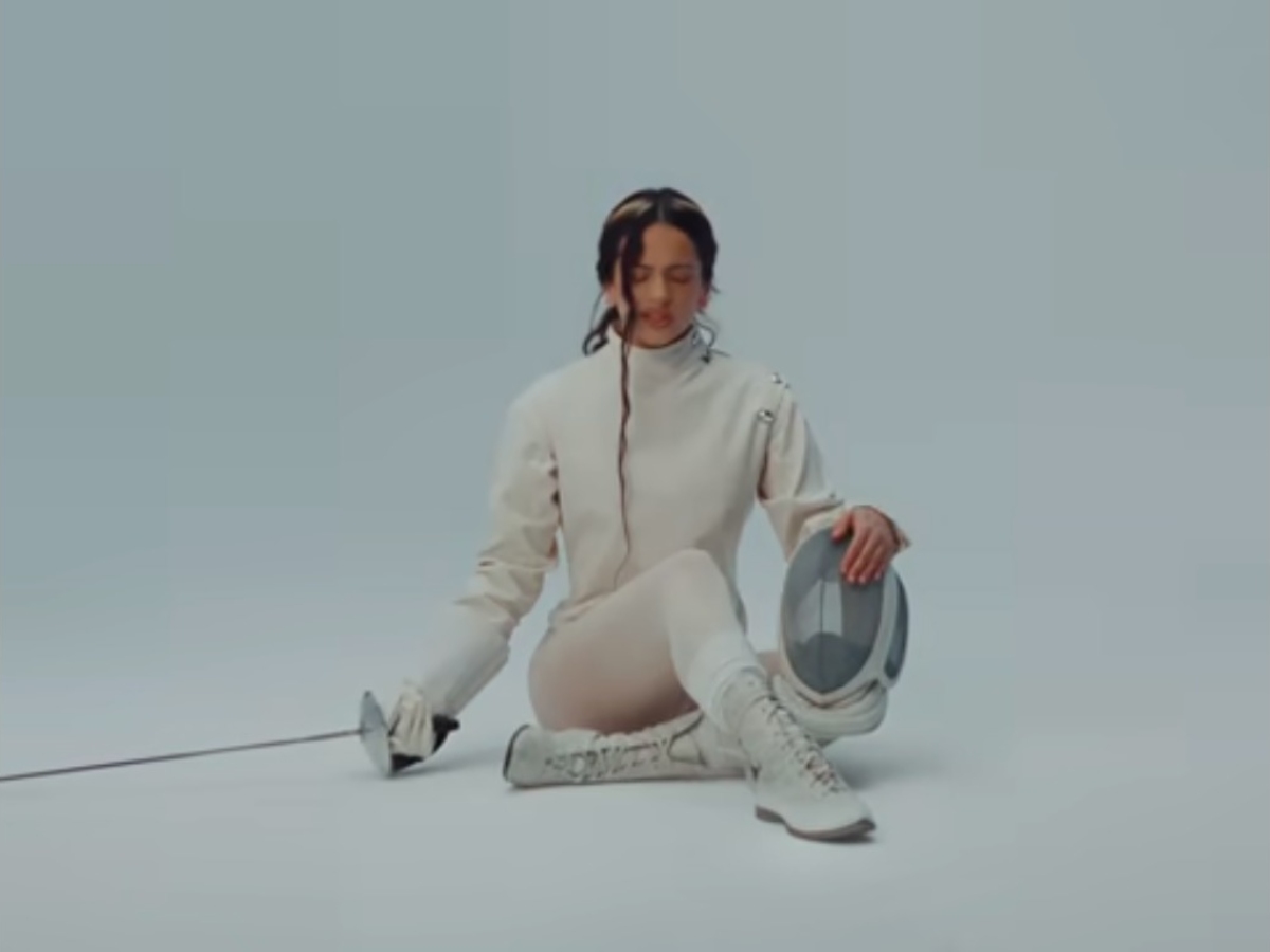 Rosalía aparece con traje de esgrima en una de las escenas del videoclip de La Perla, una imagen que refuerza la estética simbólica y contenida de su álbum Lux.
