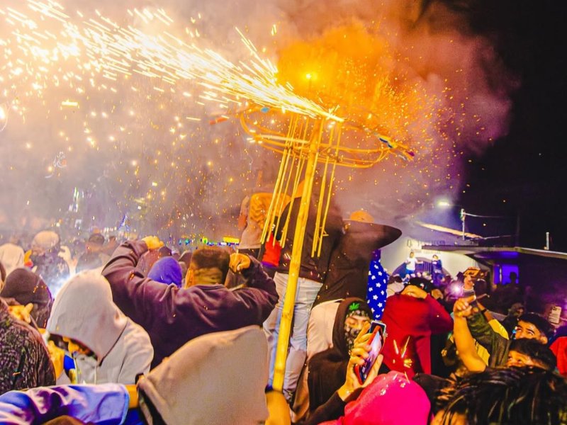 Toritos pintos recorren las calles entre luces y chispas, mientras la multitud observa con emoción.