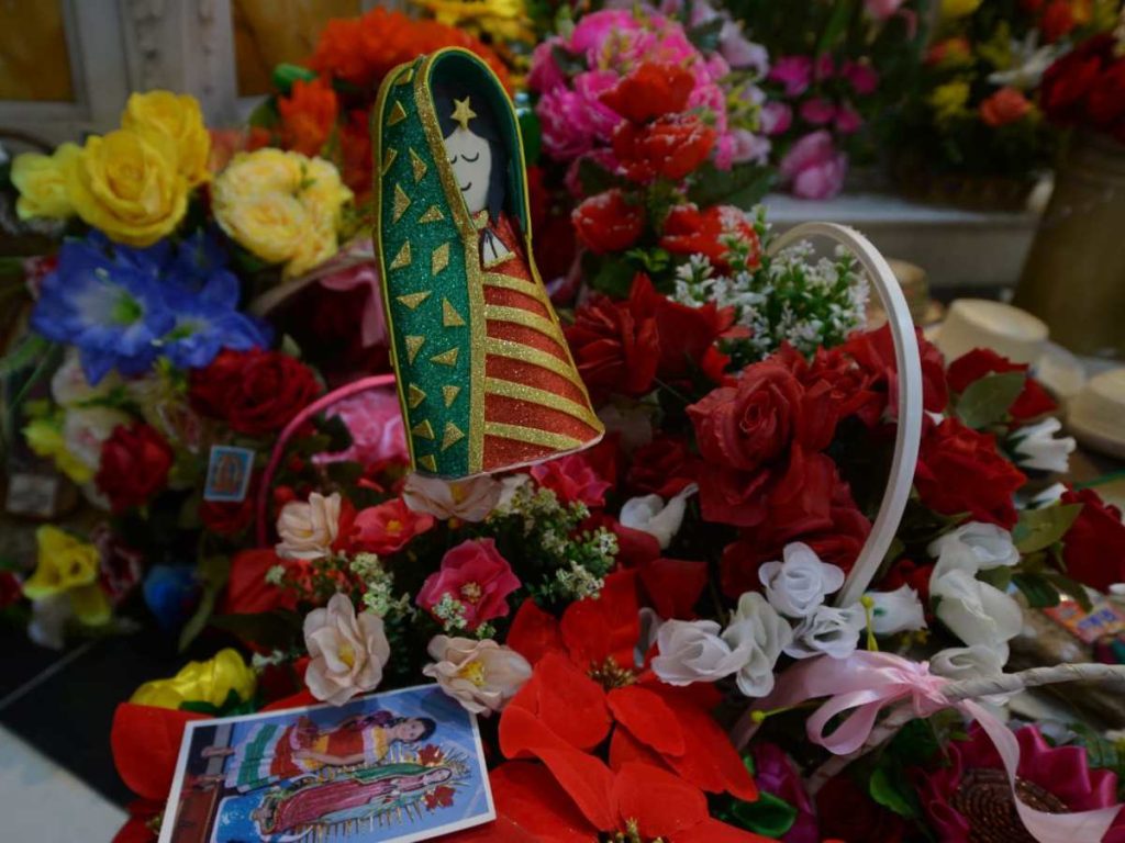 Ramos de rosas de distintos colores cubren la base del altar, una muestra del fervor de los devotos.