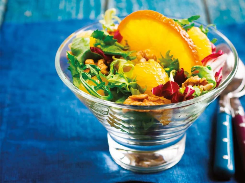 Refrescante y llena de contraste, la ensalada de naranja con hojas verdes, nueces y aderezo cítrico es perfecta para equilibrar tu menú festivo.